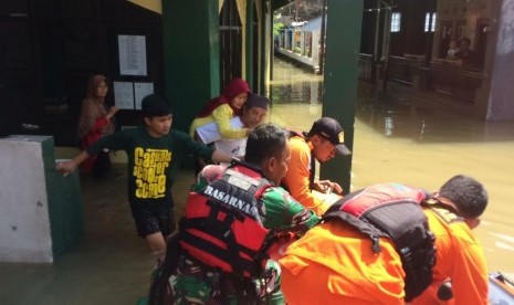  Petugas Basarnas tengah mengevakuasi warga dari rumahnya ke tempat yang  lebih aman menggunakan perahu di Baleendah, Rabu (10/4). 