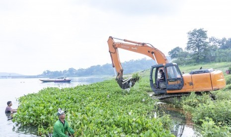 Petugas mengoperasikan alat berat saat membersihkan tanaman eceng gondok di perairan Waduk Jatiluhur, Pelabuhan Biru, Purwakarta, Jawa Barat