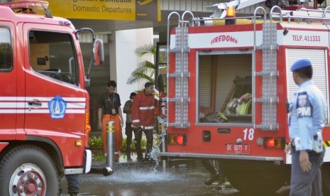 Petugas pemadam kebakaran bersiaga saat melakukan upaya pemadaman kebakaran yang terjadi di kawasanTerminal Keberangkatan Domestik Bandara Internasional I Gusti Ngurah Rai, Bali, Jumat (19/4/2019).