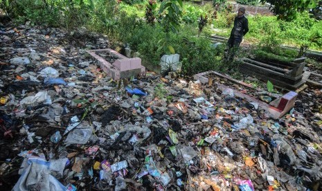 Warga menyaksikan tumpukan sampah yang menimbun makam warga di Kampung Nagrog, Kota Tasikmalaya, Jawa Barat, Selasa (23/4/2019).