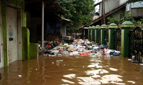 Seorang warga berusaha membersihkan sampah yang terbawa aliran banjir di kawasan permukiman penduduk Cililitan Kecil, Jakarta, Jumat (26/4/2019). 