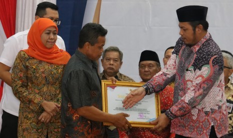 Gubernur Jawa Timur Khofifah Indar Parawansa (kiri) mendampingi Ketua Komisi Pemilihan Umum (KPU) Jawa Timur Choirul Anam (kanan) menyerahkan santunan kepada keluarga dari petugas Pemilu yang meninggal dalam tugasnya di Gedung Negara Grahadi, Surabaya, Jawa Timur, Jumat (26/4/2019).