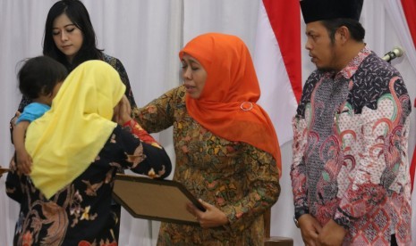 Gubernur Jawa Timur Khofifah Indar Parawansa (kedua kanan) didampingi Ketua Komisi Pemilihan Umum (KPU) Jawa Timur Choirul Anam (kanan) menyerahkan santunan kepada keluarga dari petugas Pemilu yang meninggal dalam tugasnya di Gedung Negara Grahadi, Surabaya, Jawa Timur, Jumat (26/4/2019).