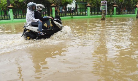 Pelajar mengendarai sepeda motor melintasi jalan yang terendam banjir di Kabupaten Madiun, Jawa Timur, Senin (29/4/2019).