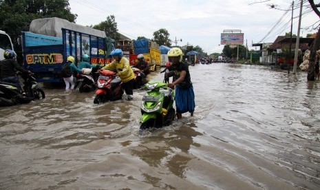 Warga mendoroang kendaraan bermotor yang mogok akibat banjir yang menggenangi kawasan Jalan Raya Pantura Kraton, Pasuruan, Jawa Timur. Jalan di wilayah Kraton Pasuruan sepanjang 1,5 kilometer ditutup karena banjir. Ilustrasi.