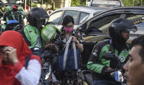 Pengendara ojek daring melayani penumpang.