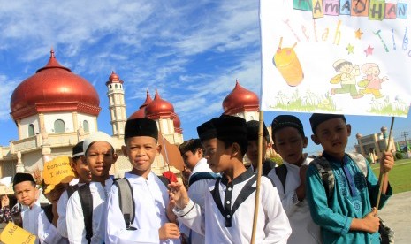 Sejumlah pelajar melintas di depan Masjid Agung Baitul Makmur Meulaboh saat mengikuti pawai sambut Ramadhan di Aceh Barat, Aceh, Jumat (3/5/2019).