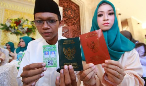 Pasangan pengantin menunjukkan buku nikah dan kartu nikah usai mengikuti acara nikah massal di Masjid Raya Sabilal Muhtadin, Banjarmasin, Kalimantan Selatan, Sabtu (4/5/2019).