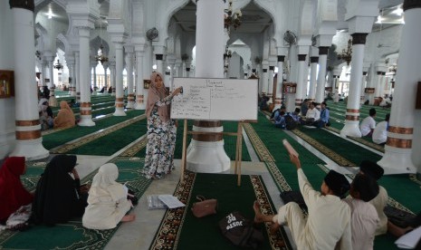 Ustazah memberikan pelajaran kepada santri di Masjid Raya Baiturrahman, Banda Aceh, Jumat (10/5/2019).