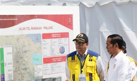 Presiden Joko Widodo (kanan) melihat peta tol Pandaan-Malang sebelum peresmian di gerbang tol Singosari, Malang, Jawa Timur, Senin (13/5/2019).