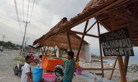 Sejumlah warga korban bencana gempa dan tsunami berjualan menu berbuka puasa (takjil) pada lapak yang didirikan disekitar rumah mereka yang rata dengan tanah di Mamboro, Palu, Sulawesi Tengah, Selasa (14/5/2019).