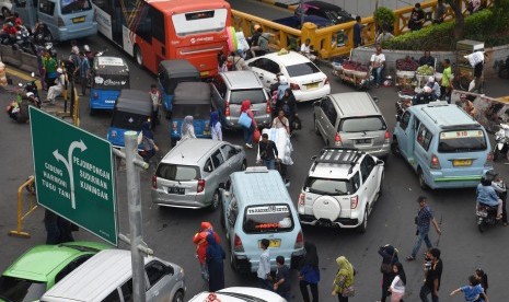 Warga dan kuli angkut menyeberang jalan di antara kendaraan bermotor yang terjebak kemacetan di kawasan Pasar Tanah Abang, Jakarta, Rabu (15/5/2019). 