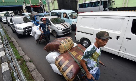 Kuli angkut melintas di antara kendaraan bermotor yang terjebak kemacetan di kawasan Pasar Tanah Abang, Jakarta, Rabu (15/5/2019). 