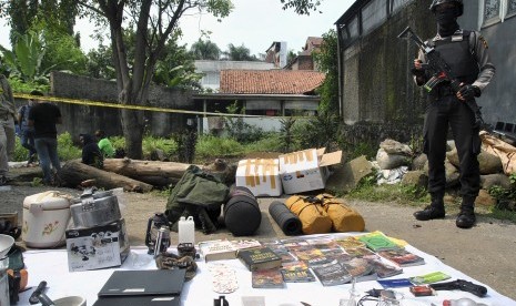 Seorang anggota polisi dengan senjata lengkap berada di dekat barang bukti terduga teroris di Kampung Nanggewer Kaum, Cibinong, Kabupaten Bogor, Jawa Barat, Sabtu (18/5/2019). 