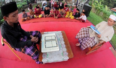 Juri (kanan) menyimak peserta lomba membaca Alquran di Kampung Beberan, Serang, Banten, Selasa (21/5/2019).