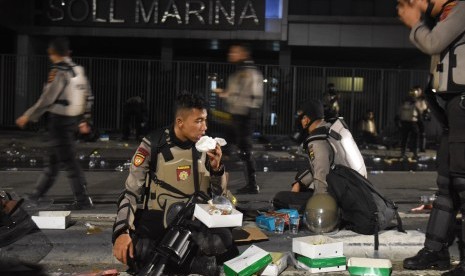 Personal polisi berbuka puasa di tengah kerusuhan aksi massa 22 Mei di Jalan Brigjen Katamso, Slip, Jakarta, Rabu (22/5/2019). 