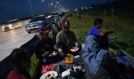 Pemudik menyantap makanan untuk berbuka puasa di pinggir ruas jalan tol Pejagan-Pemalang, Tegal, Jawa Tengah. Ahli gizi masyarakat, Tan Shot Yen, memberikan tips membawa bekal makanan yang sehat agar terhindar dari diare selama perjalanan mudik.