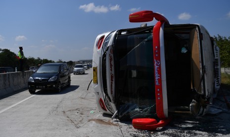 Anggota Satlantas Polres Sragen mengatur laju kendaraan yang melintas di dekat bus Sindoro Satriamas yang terguling di Jalan Tol Ngawi-Solo KM 525, Sragen, Jawa Tengah, Sabtu (1/6/2019). 