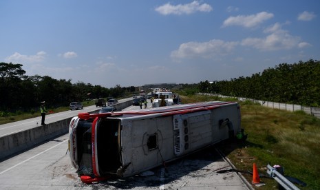 Anggota Satlantas Polres Sragen mengatur laju kendaraan yang melintas di dekat bus Sindoro Satriamas yang terguling di Jalan Tol Ngawi-Solo KM 525, Sragen, Jawa Tengah, Sabtu (1/6/2019). 