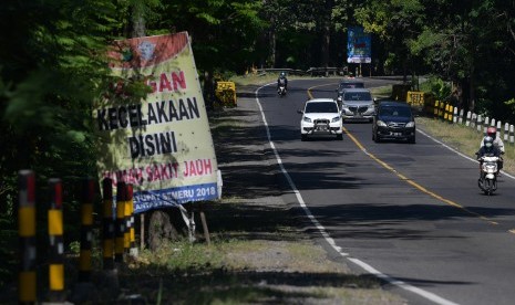 Pengendara mobil dan motor melintas di dekat spanduk himbauan hati-hati berkendara di Jalan Raya Ngawi-Solo, Ngawi, Jawa Timur, Sabtu (1/6/2019). 