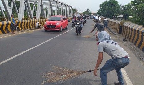 Penyapu uang koin di jembatan Kali Sewo, jalur Pantura perbatasan Kabupaten Subang dan Indramayu, Senin (3/6). 