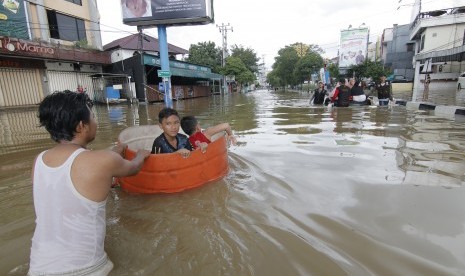 Seseorang warga mendorong drum berisi anak-anaknya yang bermain banjir di kawasan Jalan dr Soetomo di Samarinda, Kalimantan Timur, Senin (10/6/2019). 