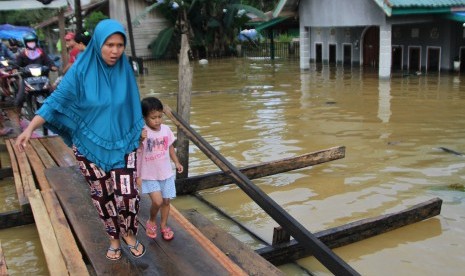 Warga melintasi jembatan darurat yang baru dibuat akibat terus naiknya ketinggian banjir di Kelurahan Sampara, Konawe, Sulawesi Tenggara, Jumat (14/6/2019).