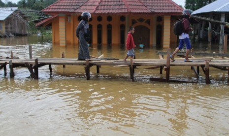 Warga melintasi jembatan darurat yang baru dibuat akibat terus naiknya ketinggian banjir di Kelurahan Sampara, Konawe, Sulawesi Tenggara, Jumat (14/6/2019).