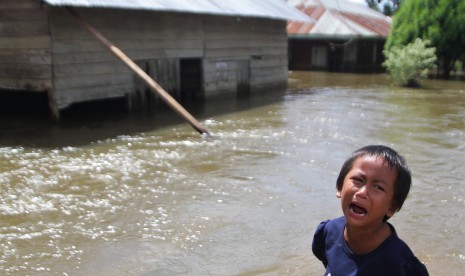 Seorang anak menangis di depan rumahnya yang terendam banjir di Desa Laikandonga, Konawe Selatan, Sulawesi Tenggara, Senin (17/6/2019).