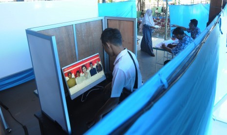 Pemilih mengamati foto calon kepala desa pada layar komputer saat melakukan pemilihan kepala desa (Pilkades) sistem 'e-voting' atau pemungutan suara berbasis elektronik di Kantor Desa Bendosari, Sawit, Boyolali, Jawa Tengah, Sabtu (29/6/2019).