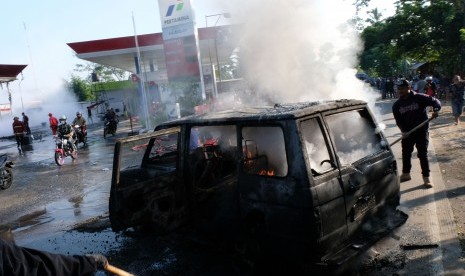 Petugas pemadam kebakaran dibantu warga berusaha memadamkan api yang membakar mobil di Stasiun Pengisian Bahan Bakar Umum (SPBU) Candiroto, Temanggung, Jawa Tengah, Senin (1/7/2019).