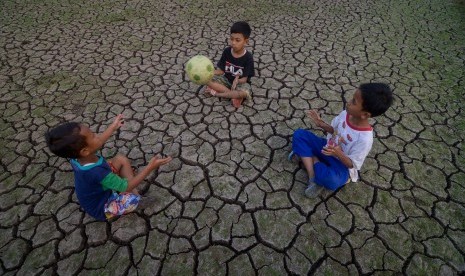 Sejumlah anak memanfaatkan areal persawahan yang terdampak kekeringan untuk bermain bola.