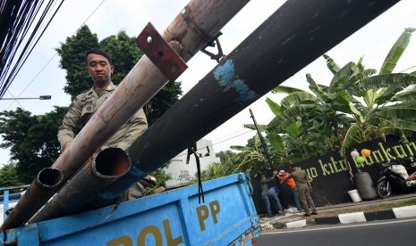 Pekerja bersama petugas Satpol PP Jakarta Selatan membongkar tiang reklame yang tak memiliki izin di kawasan Kemang, Jakarta Selatan, Rabu (3/7/2019).