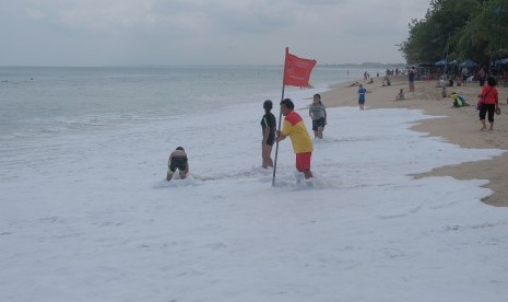 Anggota Badan Penyelamat Wisata Tirta (Balawista) memasang bendera larangan berenang saat terjadinya gelombang pasang di Pantai Kuta, Badung, Bali.