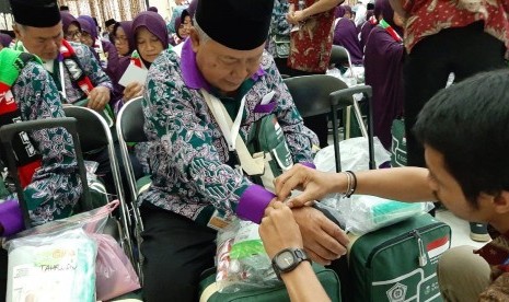 Petugas sedang memasangkan gelang identitas pada salah seorang Jamaah Calon Haji Kloter 1 dari Kabupaten Bogor di Asrama Haji Embarkasi Jakarta-Bekasi, Kota Bekasi, Sabtu (6/7).