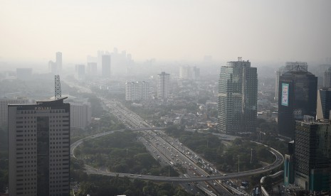 Gedung bertingkat tersamar kabut polusi udara di Jakarta, Senin (8/7/2019).