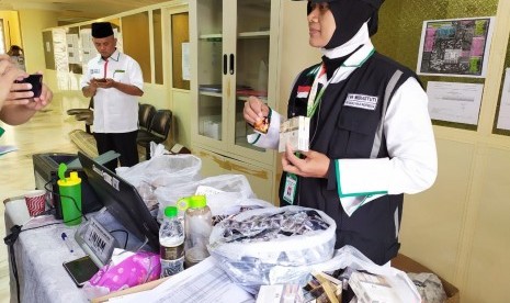 Petugas Perlindungan Jamaah (Linjam) Eva Widiastuti, menunjukkan sejumlah barang yang disita dari jamaah haji asal Embarkasi Surabaya, Jumat (12/7). Barang-barang yang disita antara lain, rokok, jamu kuat, sari rapet, dan lainnya. 