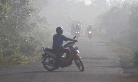 Sejumlah pengendara menembus kabut asap yang menutupi kawasan jalan di Desa Suak Nie, Kecamatan Johan Pahlawan, Aceh Barat, Senin (15/7/2019).