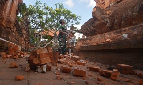 Prajurit TNI memantau kerusakan pada bagian candi yang runtuh akibat gempa di Pura Lokanatha, Denpasar, Bali, Selasa (16/7/2019).