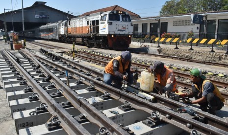 Pekerja memasang rel pada bantalan saat pembangunan jalur ganda kereta api (KA) lintas selatan di kawasan Stasiun KA Madiun, Jawa Timur, Rabu (17/7/2019). 