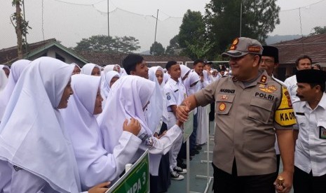 Para pelajar MAN 1 Kabupaten Sukabumi bersalaman dengan Kapolres Sukabumi AKBP Nasriadi setelah mengikuti upacara bendera dan ramai berita pengibaran bendera tauhid, Senin (22/7)