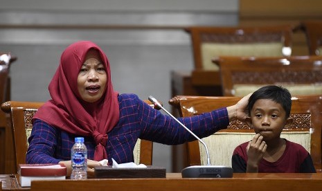 Terpidana kasus pelanggaran Undang-Undang Transaksi dan Informasi Elektronik (UU ITE), Baiq Nuril Maknun (kiri) didampingi anaknya menyampaikan tanggapan saat rapat pleno Komisi III DPR terkait surat persetujuan amnesti di Kompleks Parlemen Senayan, Jakarta, Selasa (23/7/2019). 