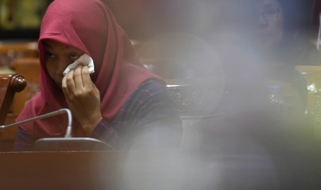 Terpidana kasus pelanggaran Undang-Undang Transaksi dan Informasi Elektronik (UU ITE), Baiq Nuril Maknun menyeka air mata saat mengikuti rapat pleno Komisi III DPR terkait surat persetujuan amnesti di Kompleks Parlemen Senayan, Jakarta, Selasa (23/7/2019). 