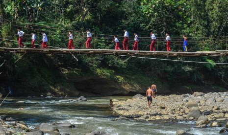 Siswa Sekolah Dasar (SD) menyeberangi Jembatan Gantung Lengkongjaya yang melintasi Sungai Ciwulan, Desa Pusparaja, Kabupaten Tasikmalaya, Jawa Barat, Selasa (23/7/2019). 