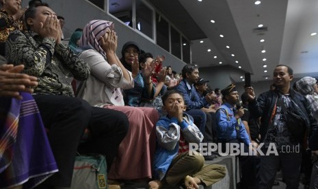 Ekspresi terpidana kasus pelanggaran Undang-Undang Transaksi dan Informasi Elektronik (UU ITE), Baiq Nuril Maknun (tengah) didampingi kerabat saat pengesahan amnesti untuk dirinya pada rapat paripurna DPR di Kompleks Parlemen Senayan, Jakarta, Kamis (25/7/2019).