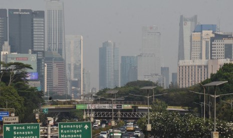 Kendaraan melintas dengan latar belakang gedung bertingkat yang tersamar polusi di kawasan Gatot Subroto, Jakarta, Ahad (28/7/2019). 