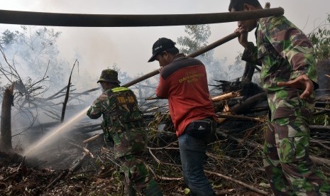 Sejumlah personel TNI Koramil 09 Langgam bersama pemadam kebakaran PT Riau Andalan Pulp and Paper (RAPP) berusaha memadamkan kebakaran lahan gambut di Desa Penarikan Kecamatan Langgam Kabupaten Pelalawan, Riau, Ahad (28/7/2019). 