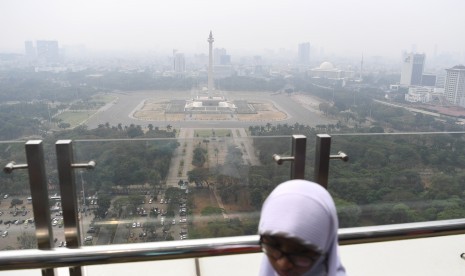 Warga beraktivitas dengan latar belakang suasana gedung bertingkat yang diselimuti asap polusi di Jakarta, Senin (29/7/2019).