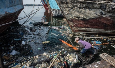 Pekerja membersihkan sampah yang terbawa arus di kawasan pesisir Muara Baru, Jakarta, Rabu (31/7/2019).