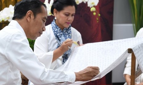 Presiden Joko Widodo (kiri) bersama Ibu Negara Iriana Joko Widodo (kanan) mencanting batik motif Gurdo di kain sepanjang 74 meter saat menghadiri kegiatan Batik Kemerdekaan di Stasiun MRT Bundaran HI Jakarta, Kamis (1/8/2019).